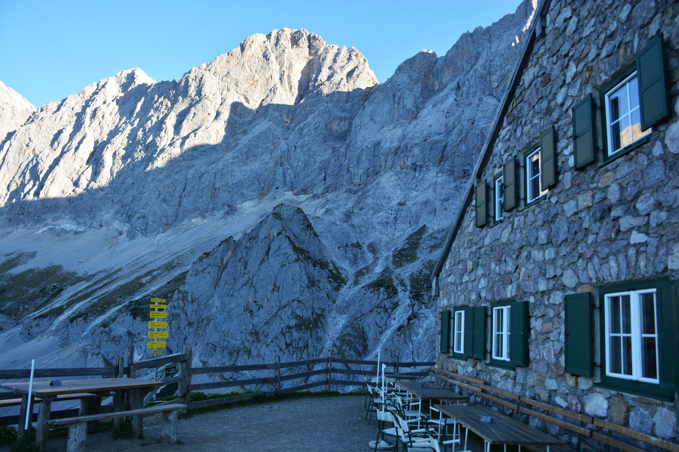Steinhaus vor einer beindruckenden grauen Gipfelkette im Hintergrund