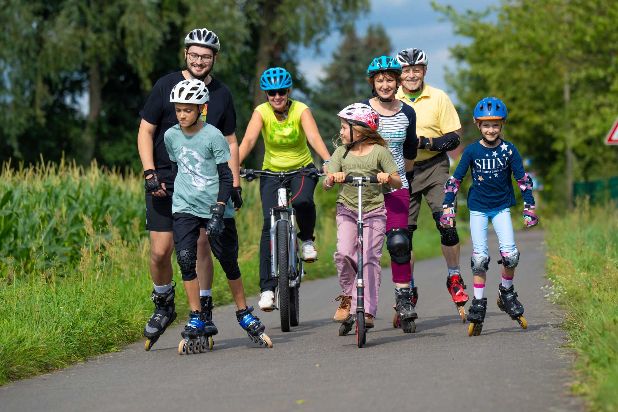 Eine Familie mit Inlinern, Fahrrad und Roller