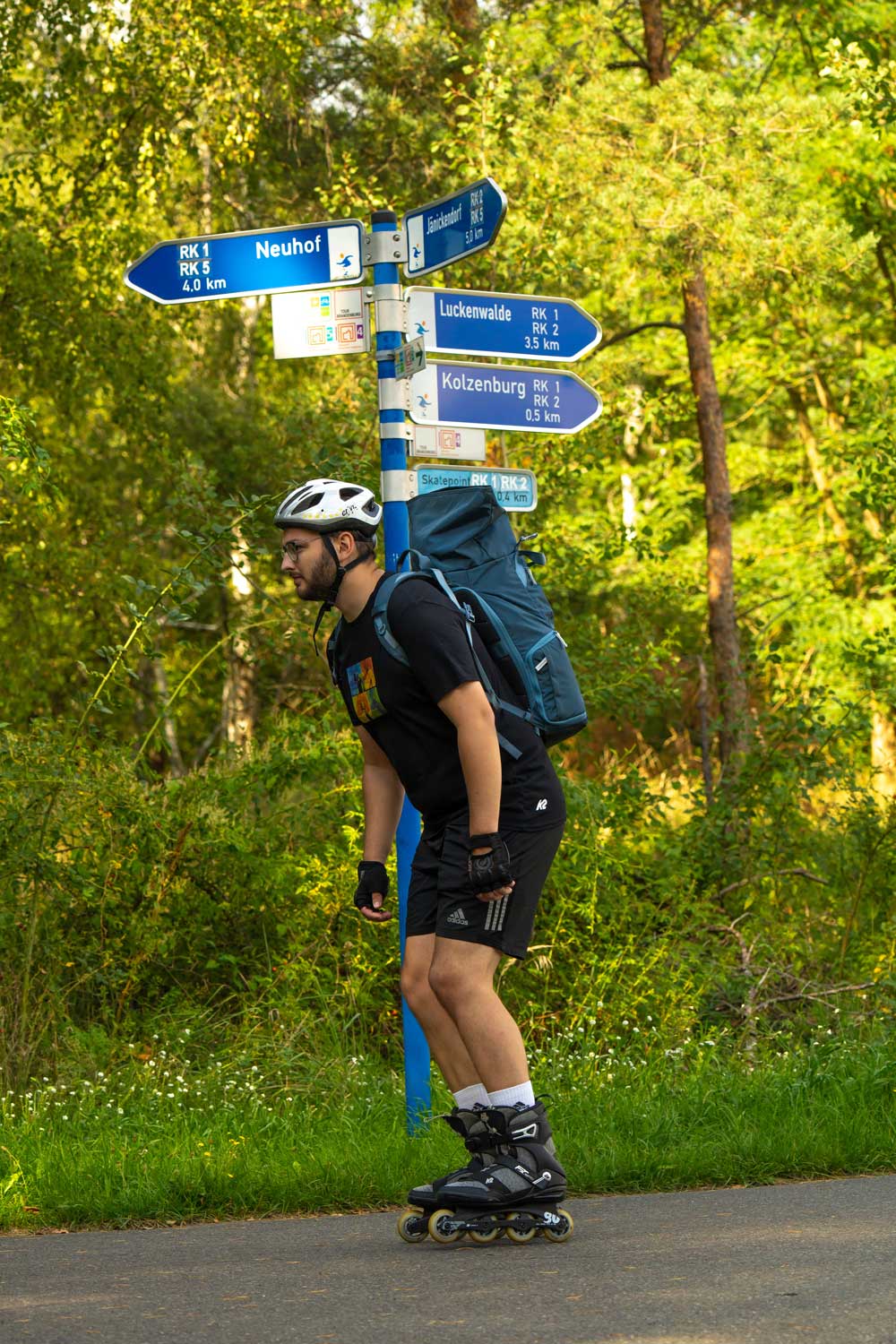 Ein Mann mit Inlinern vor einem Wegweiser