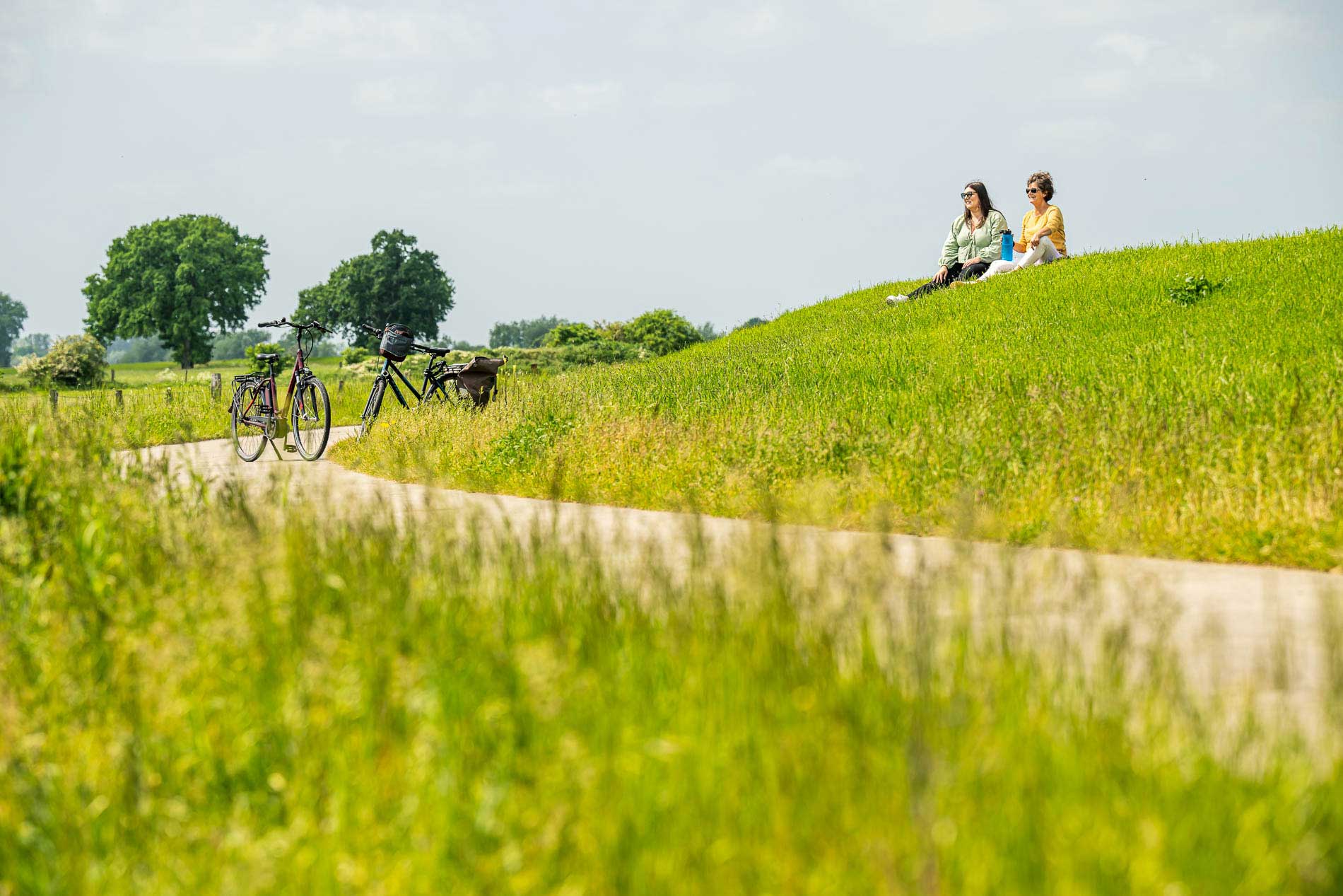 Zwei Frauen sitzen auf einer Wiese und haben die Fahrräder abgestellt