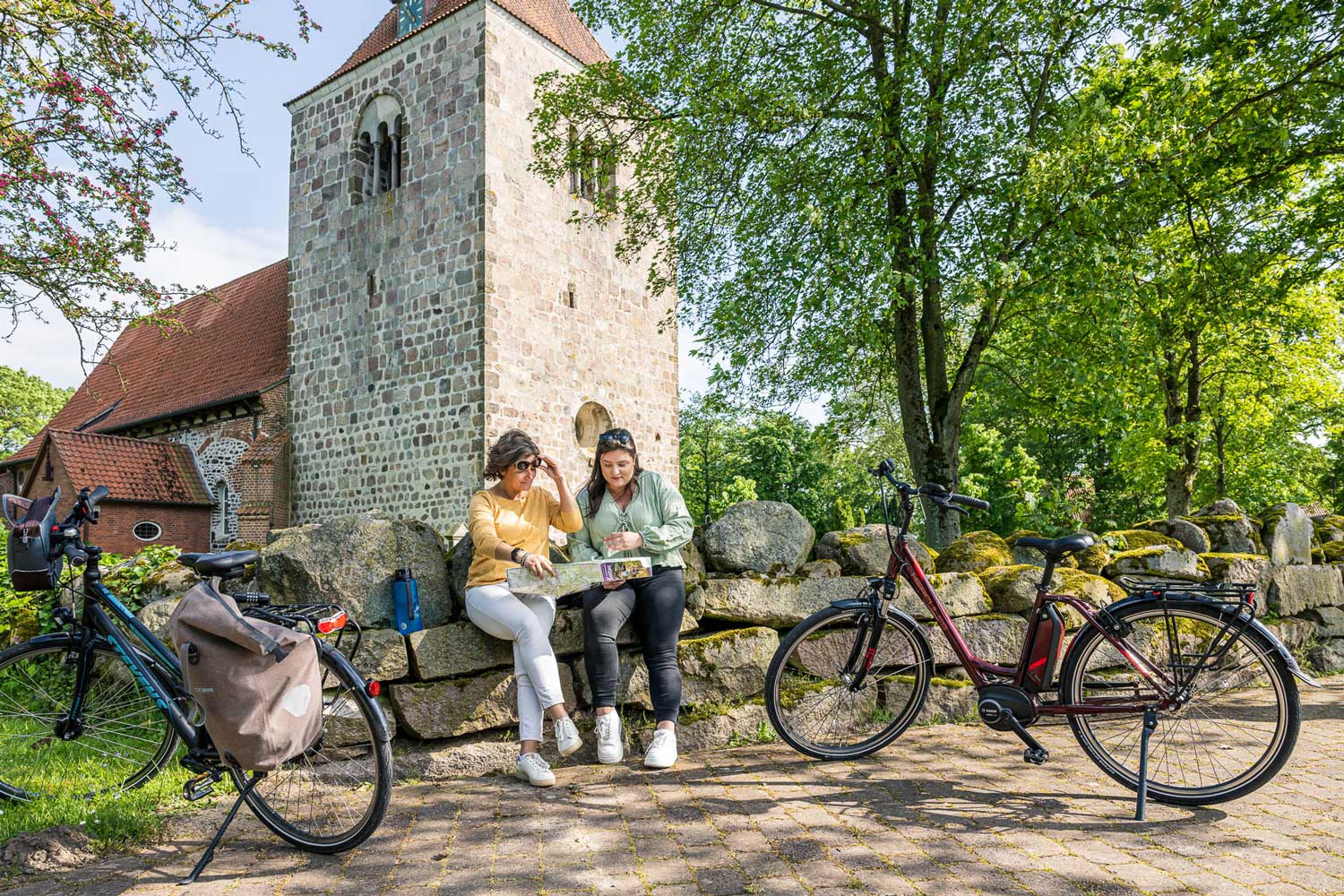 Zwei Frauen sitzen vor einem historischen Gebäude und lesen eine Karte