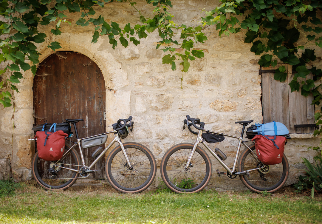 Zwei bepackte Fahrräder parken an einer steinernen Hauswand mit grünen ranken
