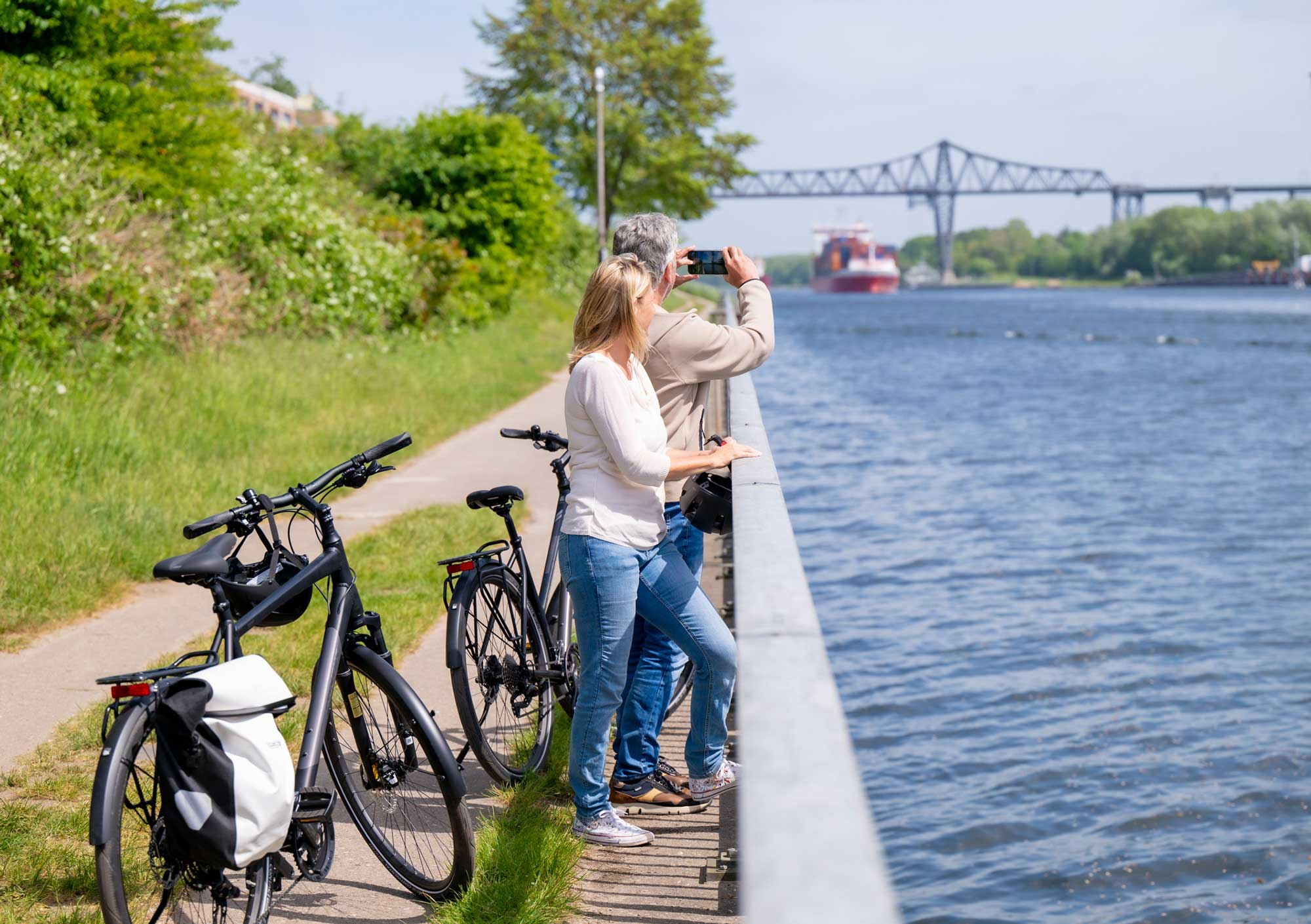 Zwei Radfahrer:innen machen Pause am Wasser