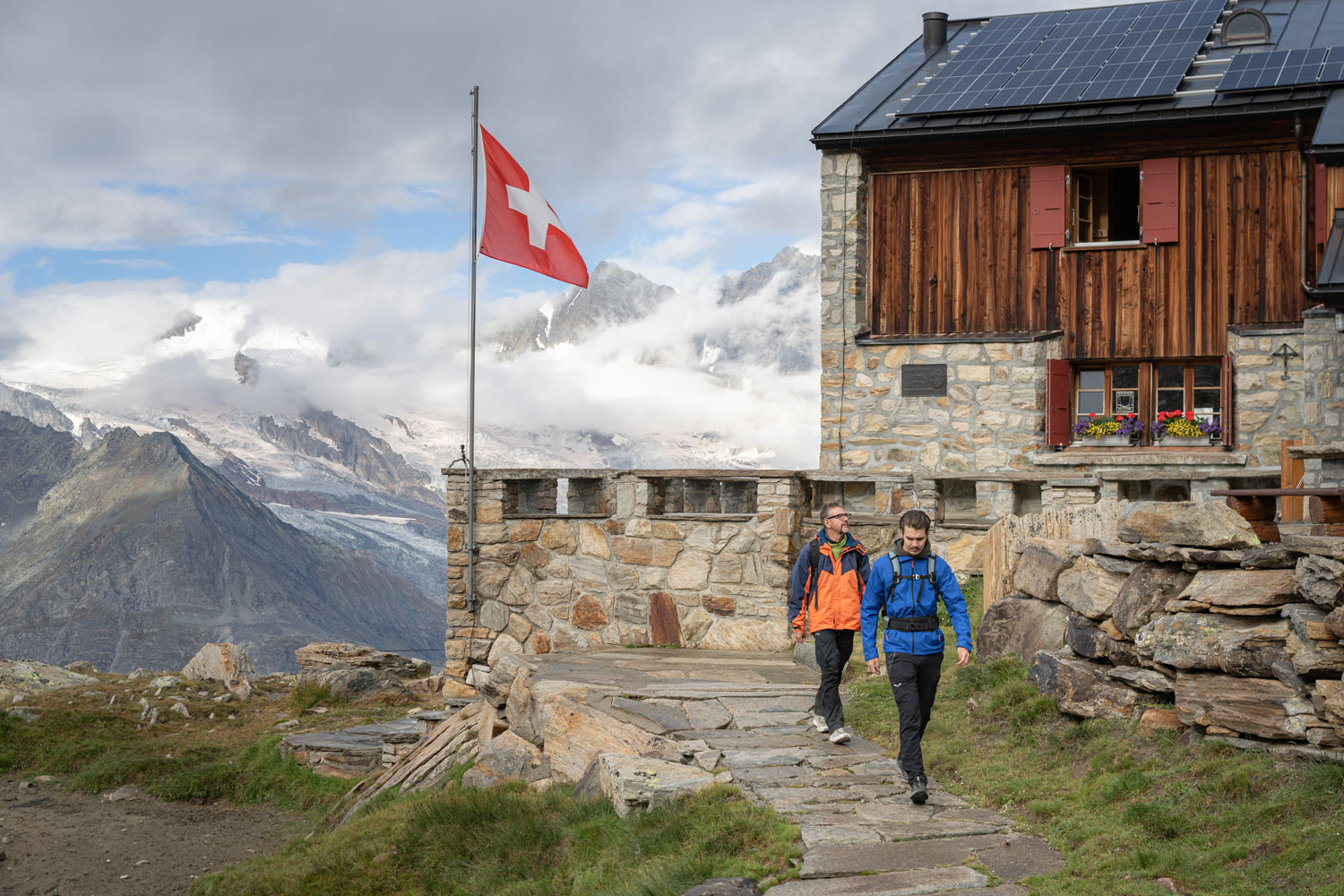 Zwei Wanderer an eine traditionellen Hütte im Saastal