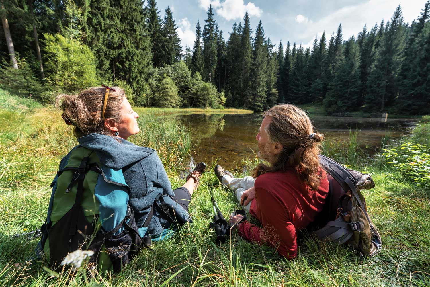 Zwei Wandernde sitzen an einem See im Wald 
