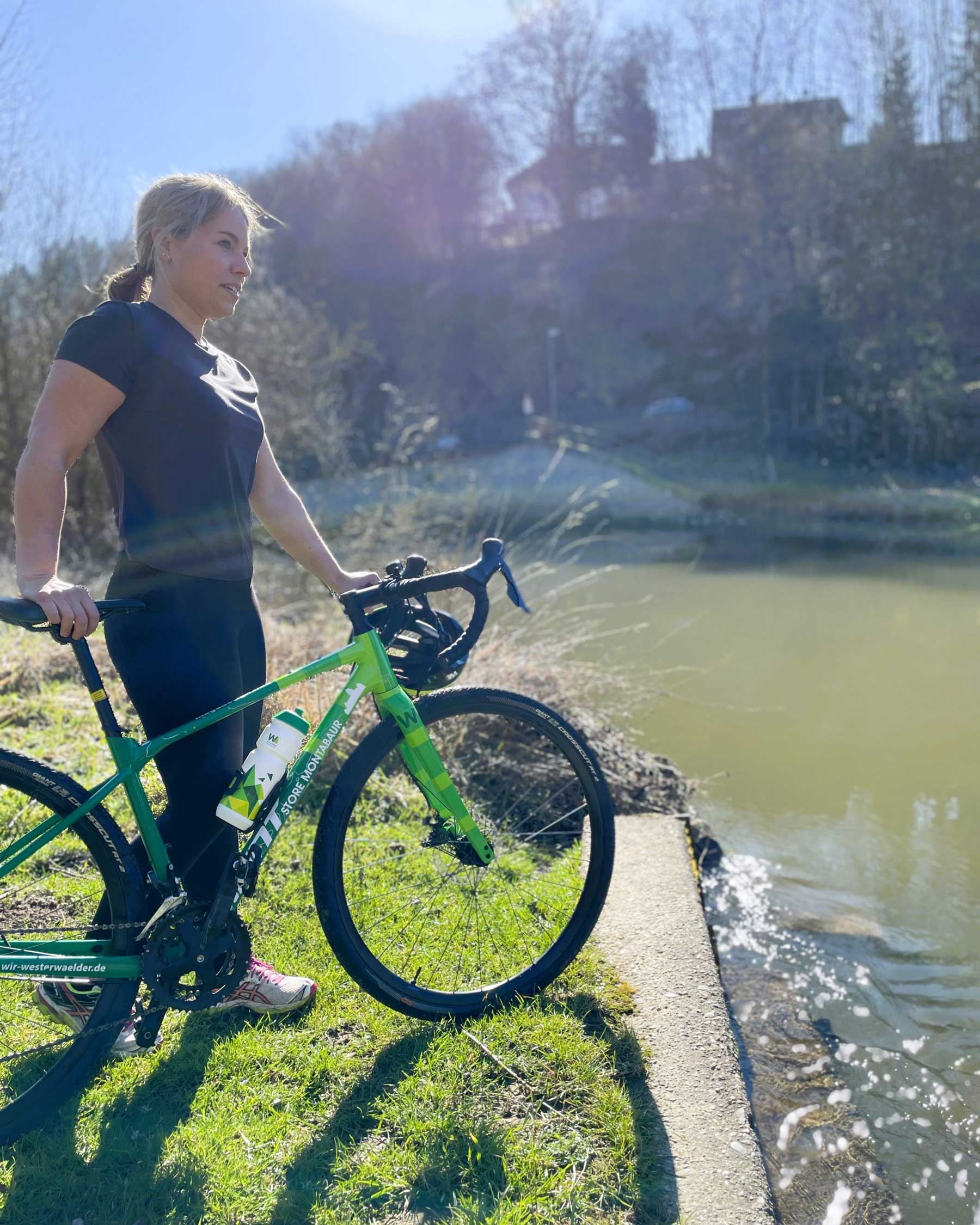 Frau mit Gravelbike an Flussufer